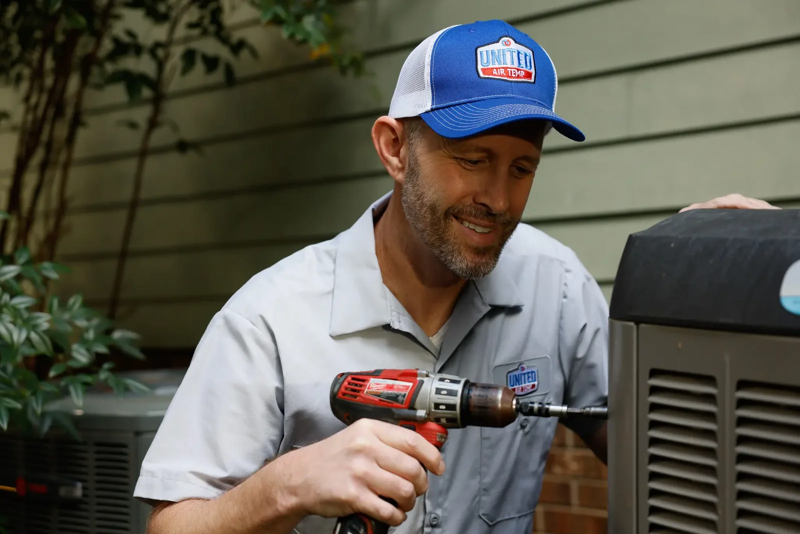HVAC technician servicing a residential air conditioning condenser