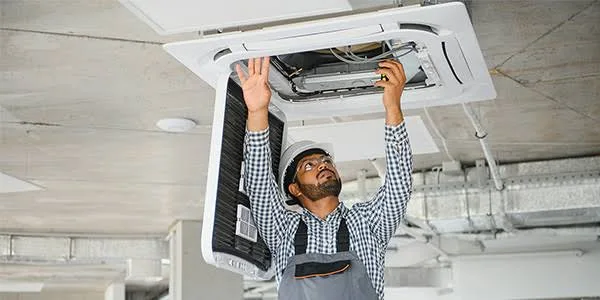Technician inspecting an outdoor HVAC condenser